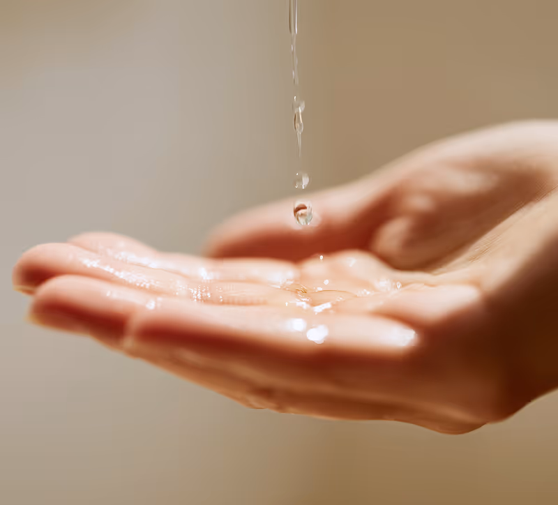 Close-up of a hand with water droplets falling onto the palm.